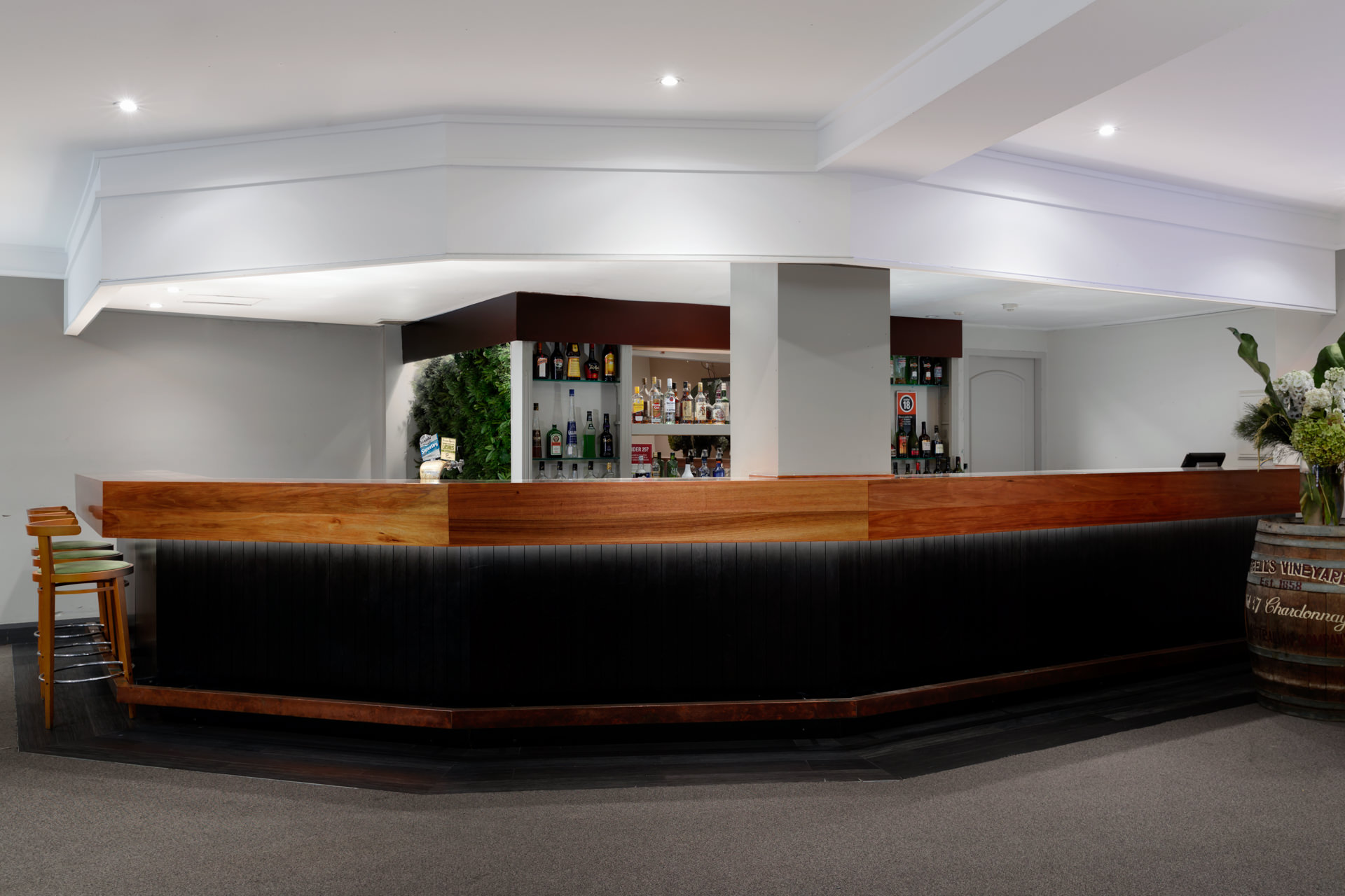 A long curved dark bar with wood trim fills the foreground, with bottles displayed on shelves behind it.